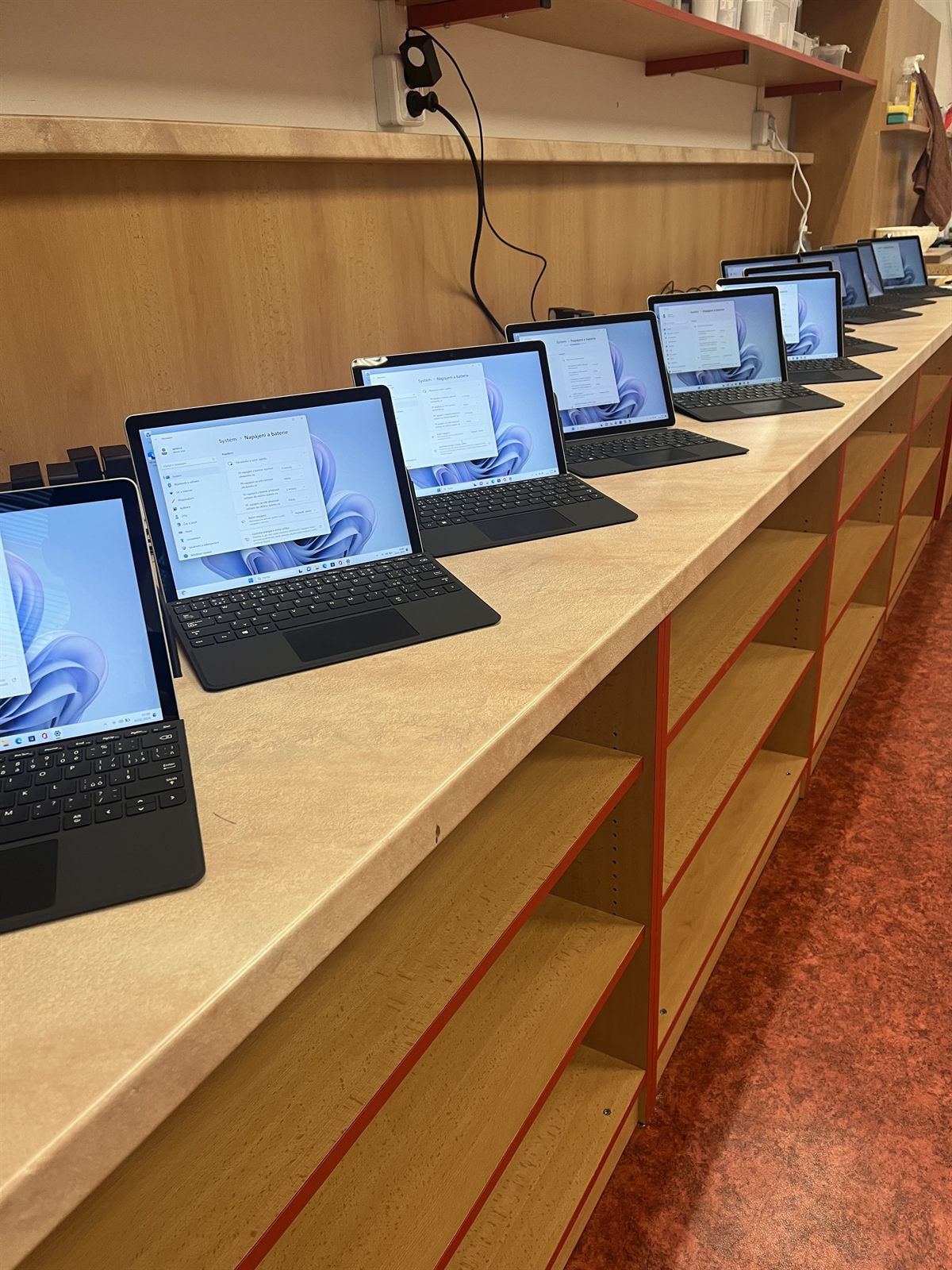 A row of 2-in-1 laptops set out along a classroom counter at ZŠ Montessori Kladno, each on a Windows configuration screen.